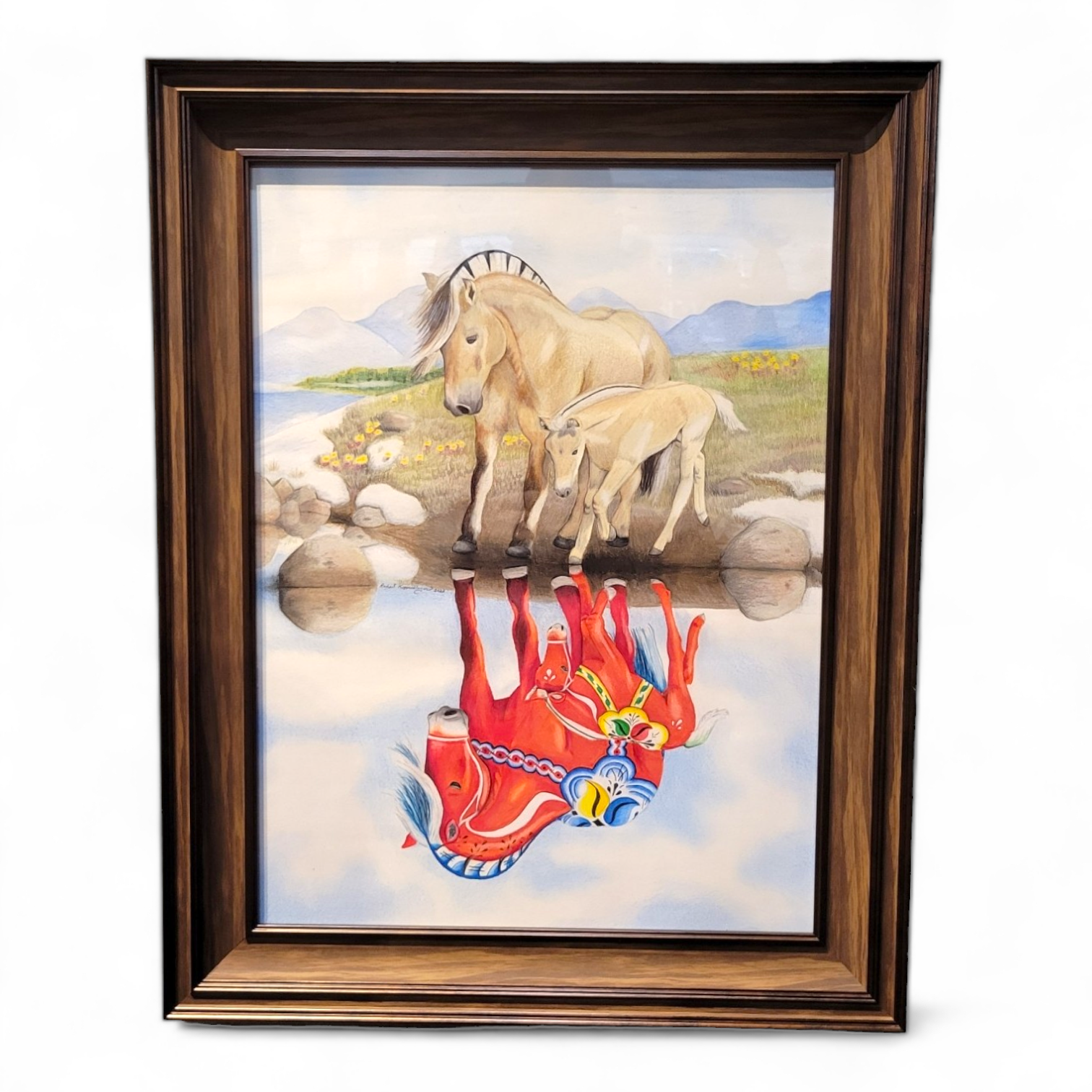 This 23x29 framed artwork, titled "Norwegian Fjord Reflection," features a Norwegian Fjord horse and foal near a water source. Their reflections depict two stylized red horses, beautifully capturing the essence of Rachael Koppendrayer's original creation.